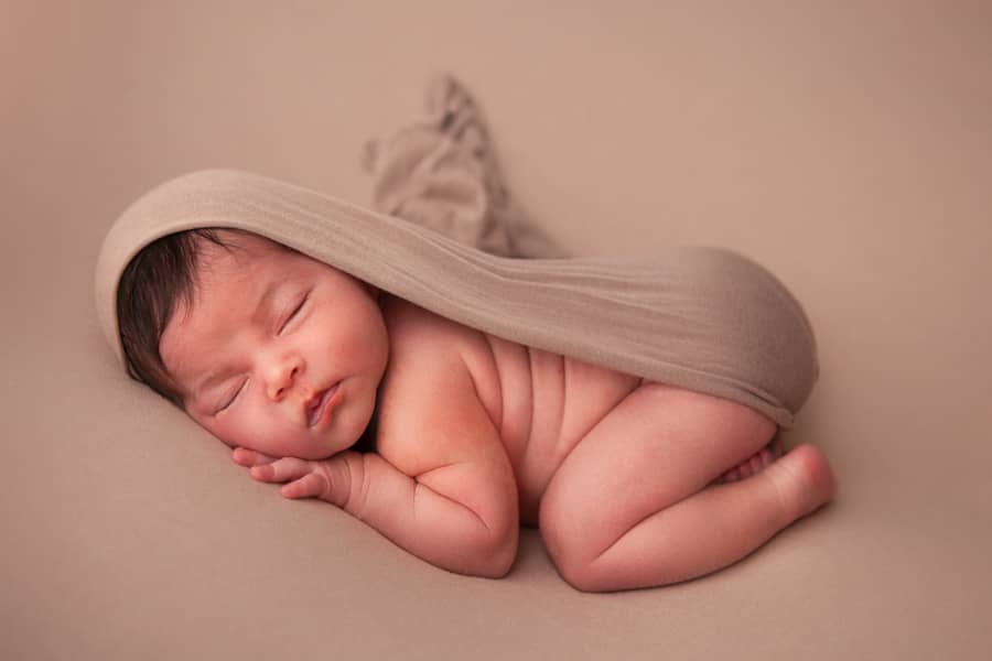 Newborn fotografie slapende baby in beige doek